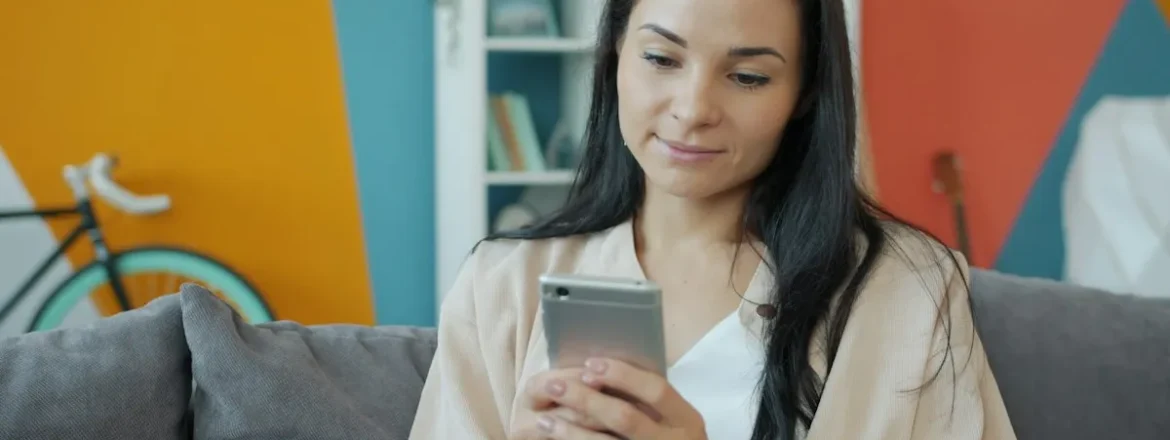 Woman relaxing on a sofa and looking at her smartphone
